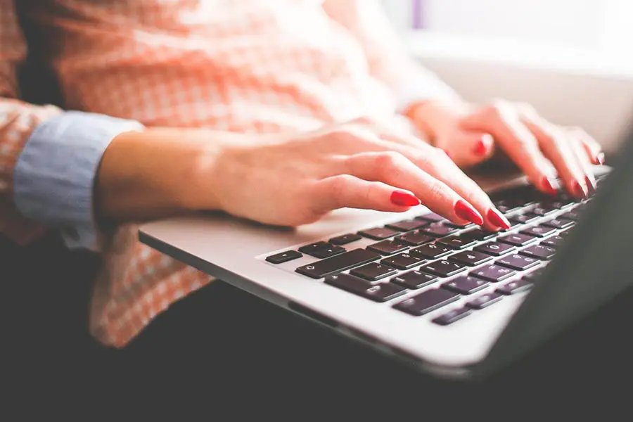 manos de mujer tecleando en el teclado de un portátil